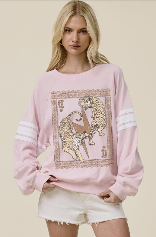 Woman wearing pink pullover with tiger graphics on it and shorts on plain background