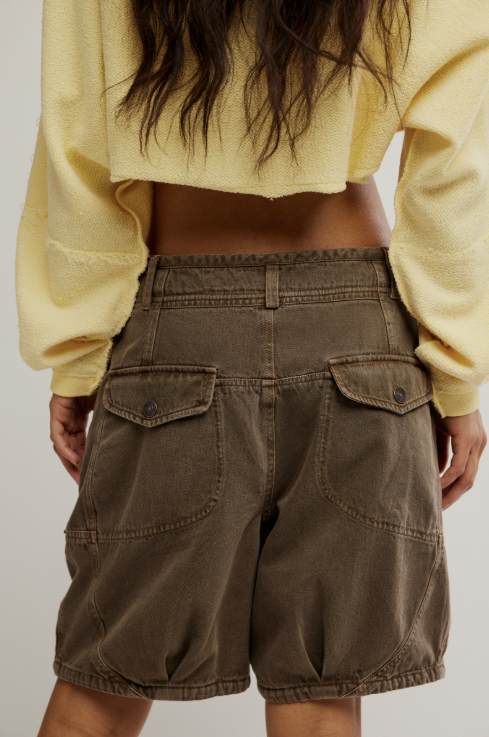 person wearing yellow cropped top and brown shorts on plain background