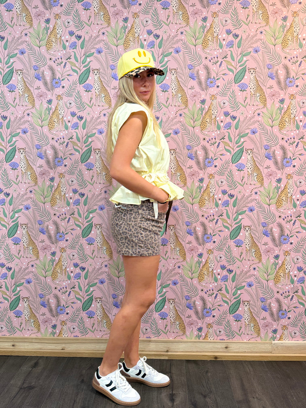 Woman wearing yellow top and leopard shorts on floral background