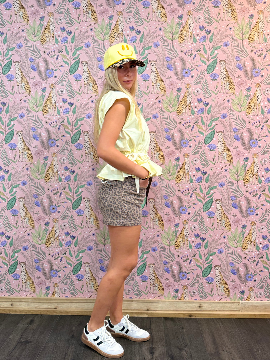 Woman wearing yellow top and leopard shorts on floral background