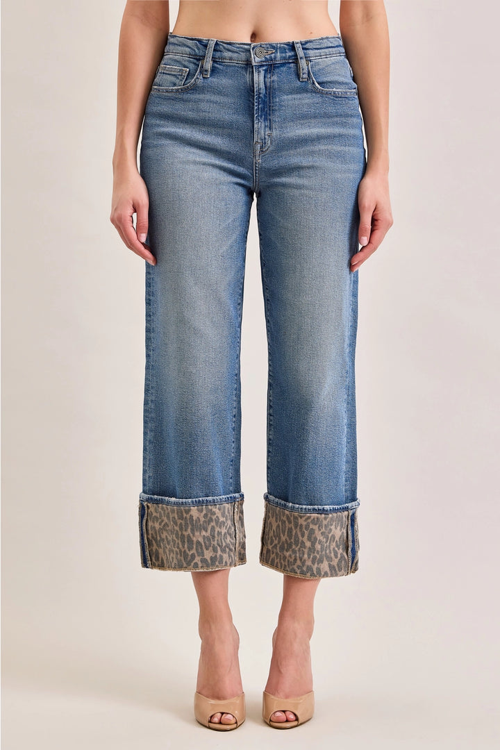 Woman wearing denim pants with leopard cuff on plain background