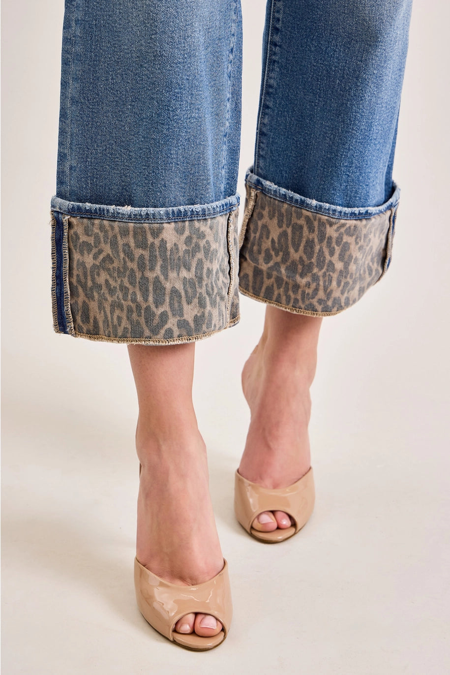 Denim jeans with leopard cuff on plain background