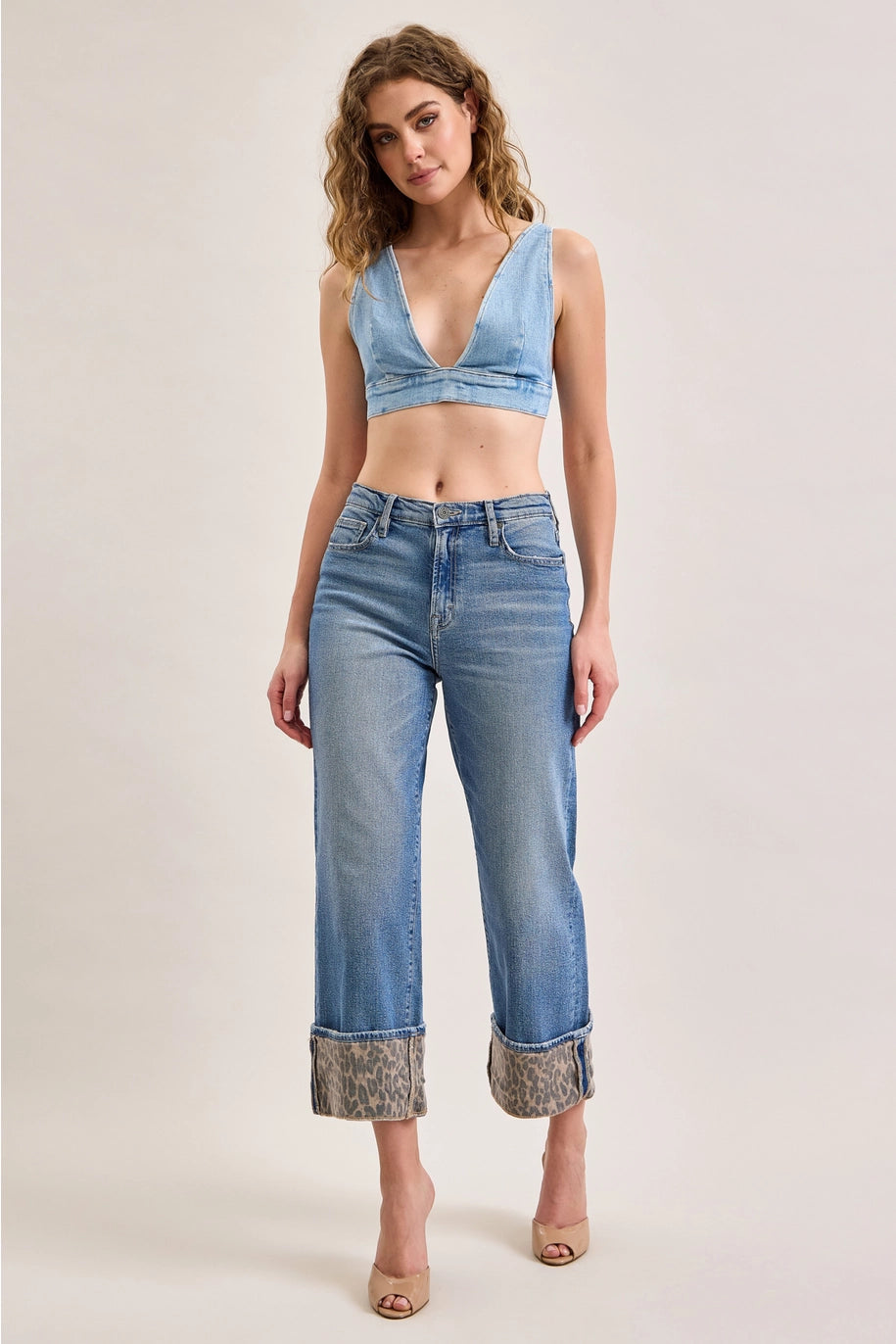 Woman wearing denim jeans with leopard cuffs on plain background
