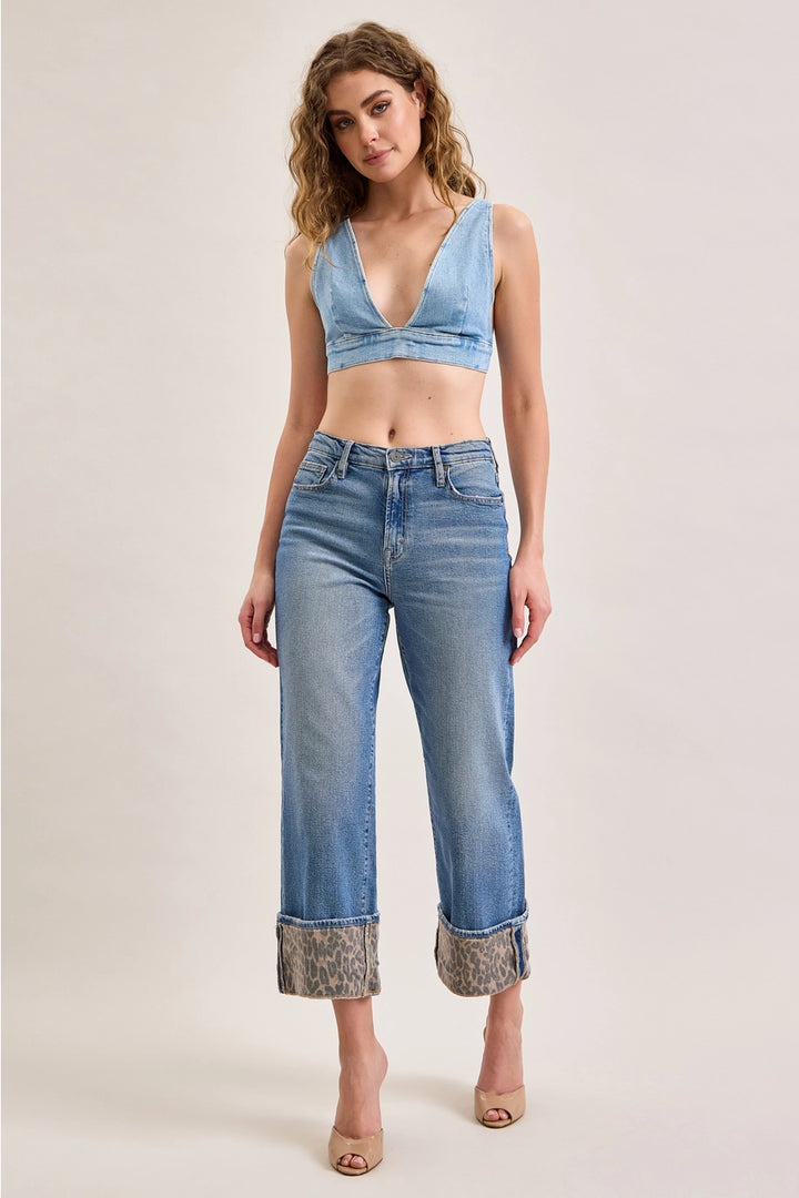 Woman wearing denim jeans with leopard cuffs on plain background