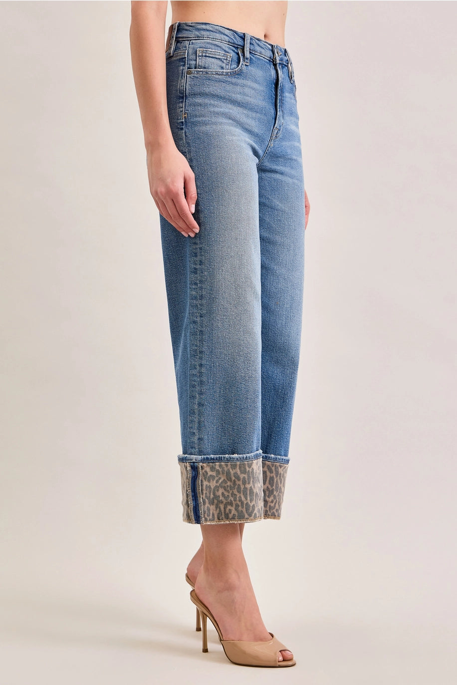 Denim jeans with leopard cuffs on plain background