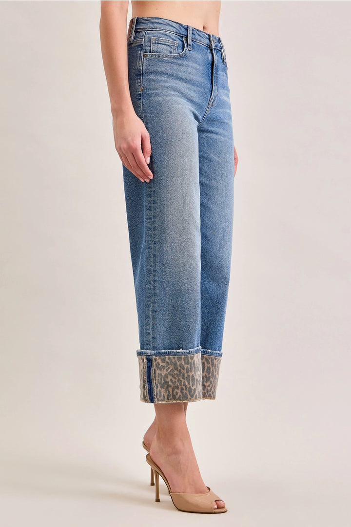 Denim jeans with leopard cuffs on plain background