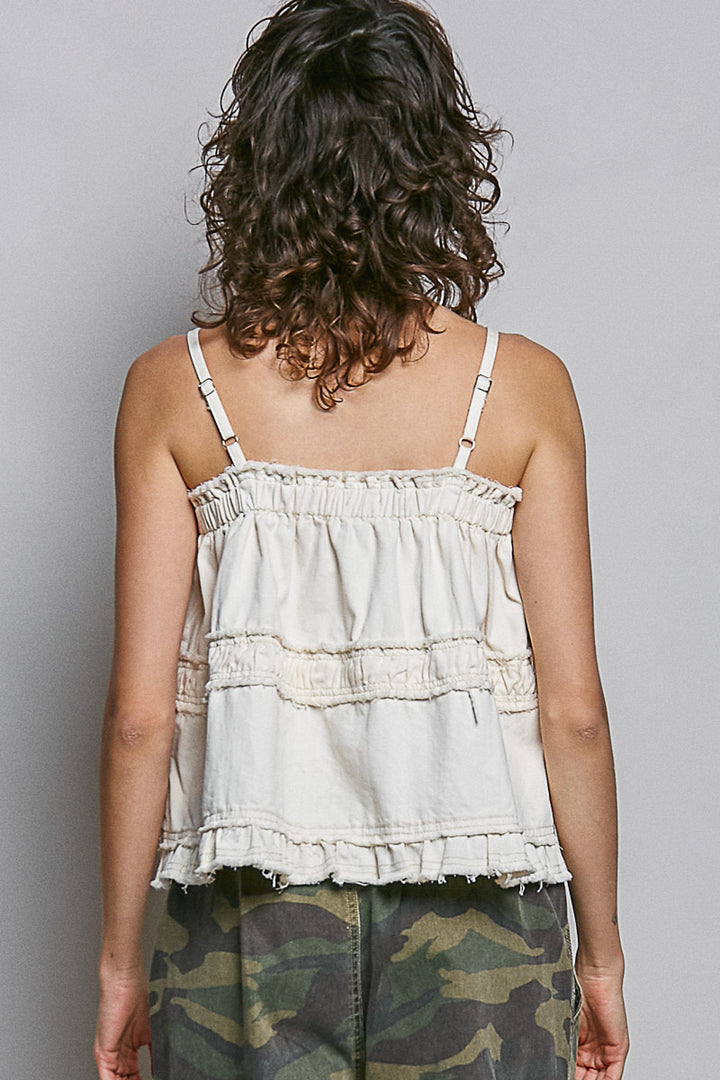 Back of woman wearing white tank and camo pants on plain background