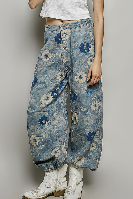 Person wearing blue floral wide-leg jeans with a plain background
