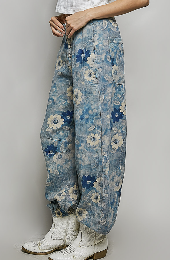 Person wearing blue floral pants with white boots on a plain background