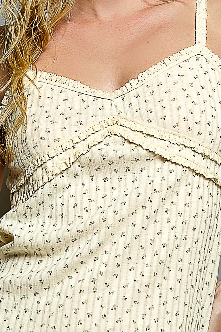 Close-up of a person wearing a light-colored tank top with floral patterns.