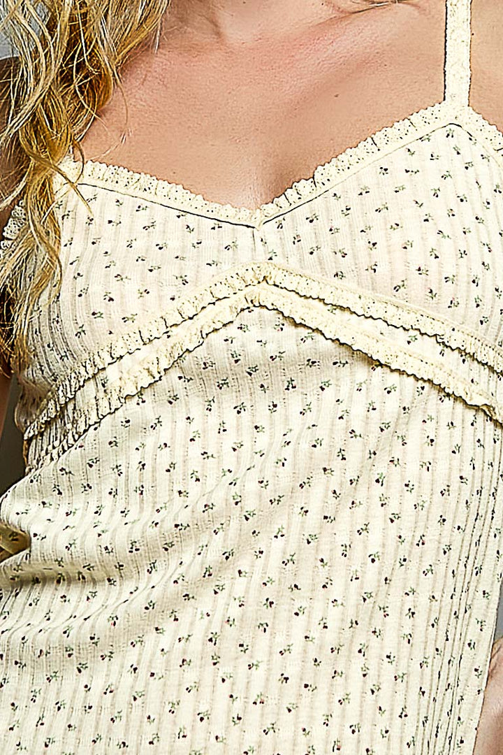 Close-up of a person wearing a light-colored tank top with floral patterns.