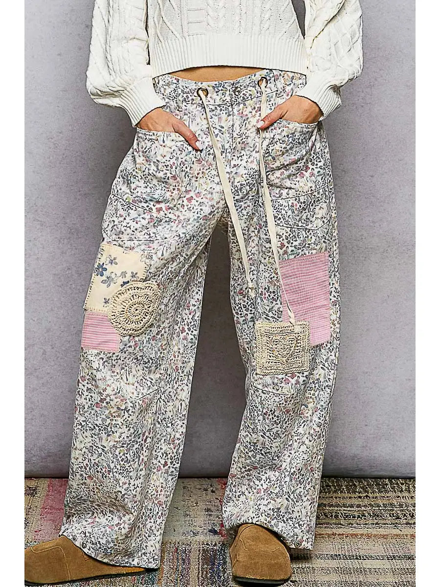 Person wearing floral patchwork pants with a plain background