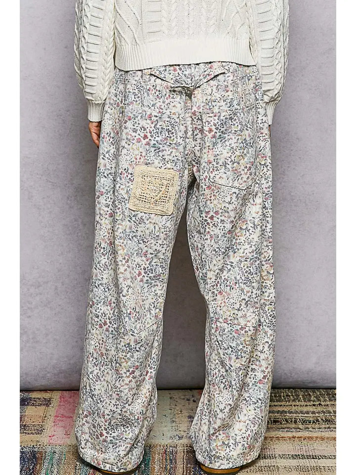 Person wearing floral-patterned pants with a plain background