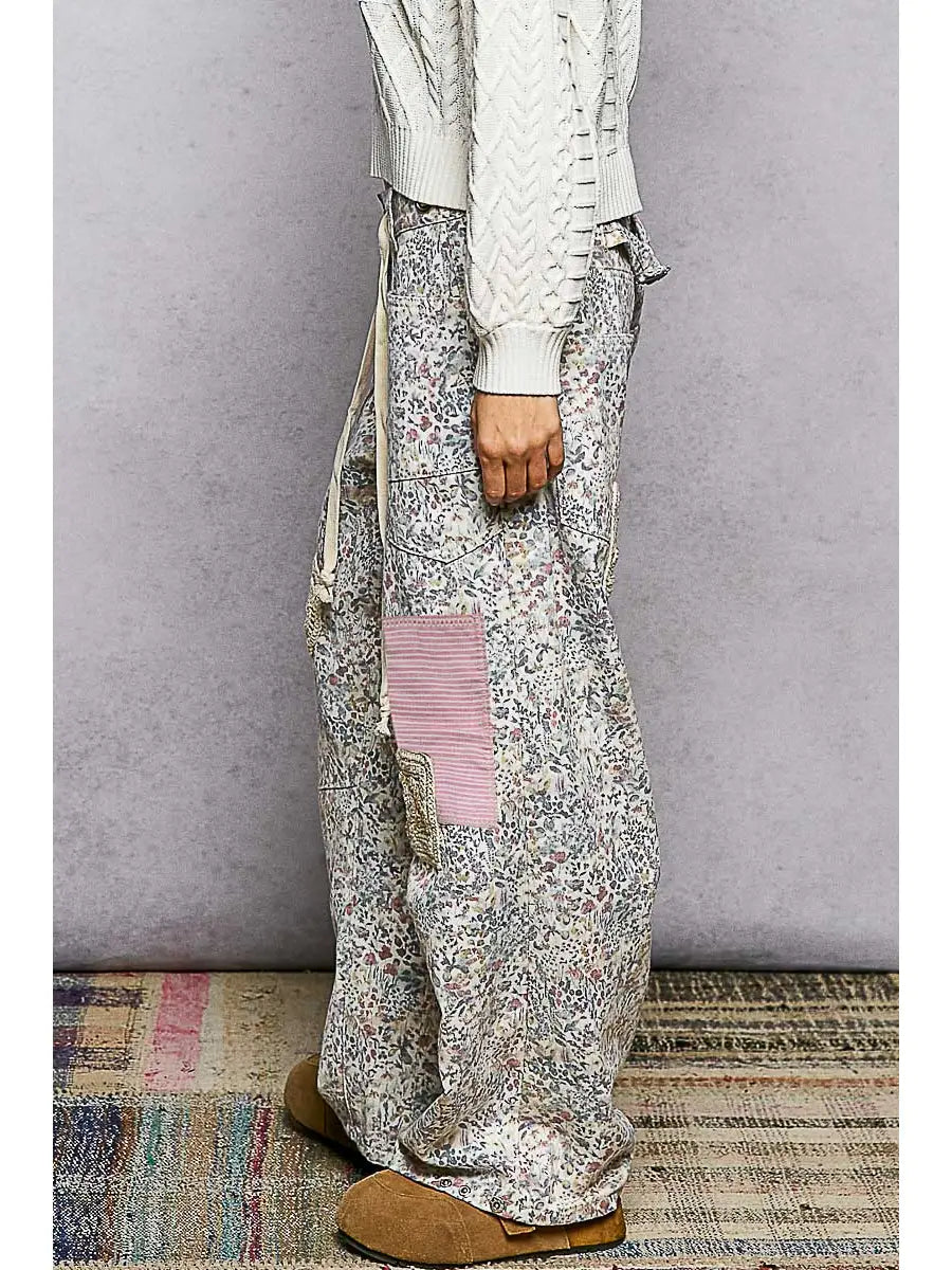 Person wearing a white sweater and patterned pants on a gray background