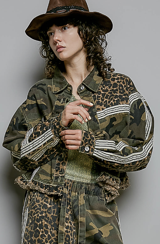Woman wearing camo and leopard style jacket and pants on plain background