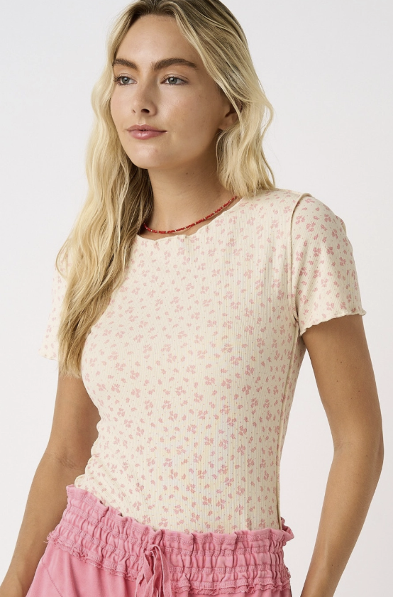 Woman wearing a floral top and pink skirt on a white background