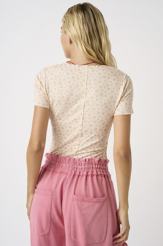 Woman wearing a floral top and pink pants on a white background