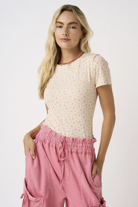 Woman wearing a patterned top and pink pants on a white background