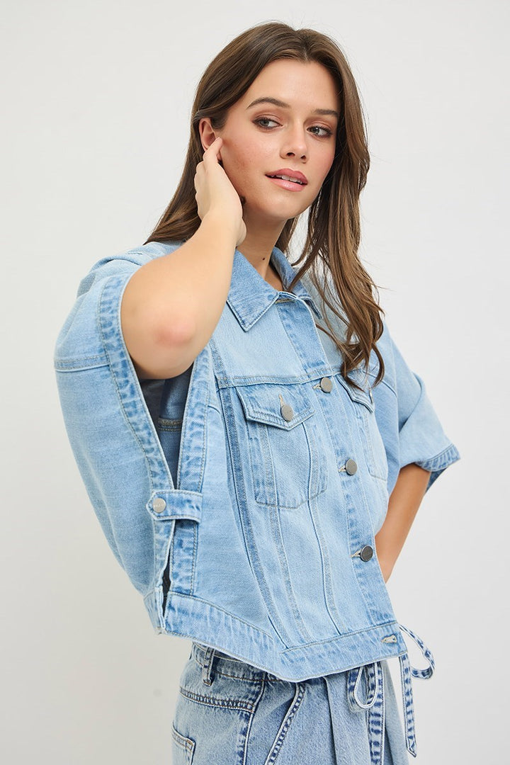 Woman wearing denim cape jacket on plain background
