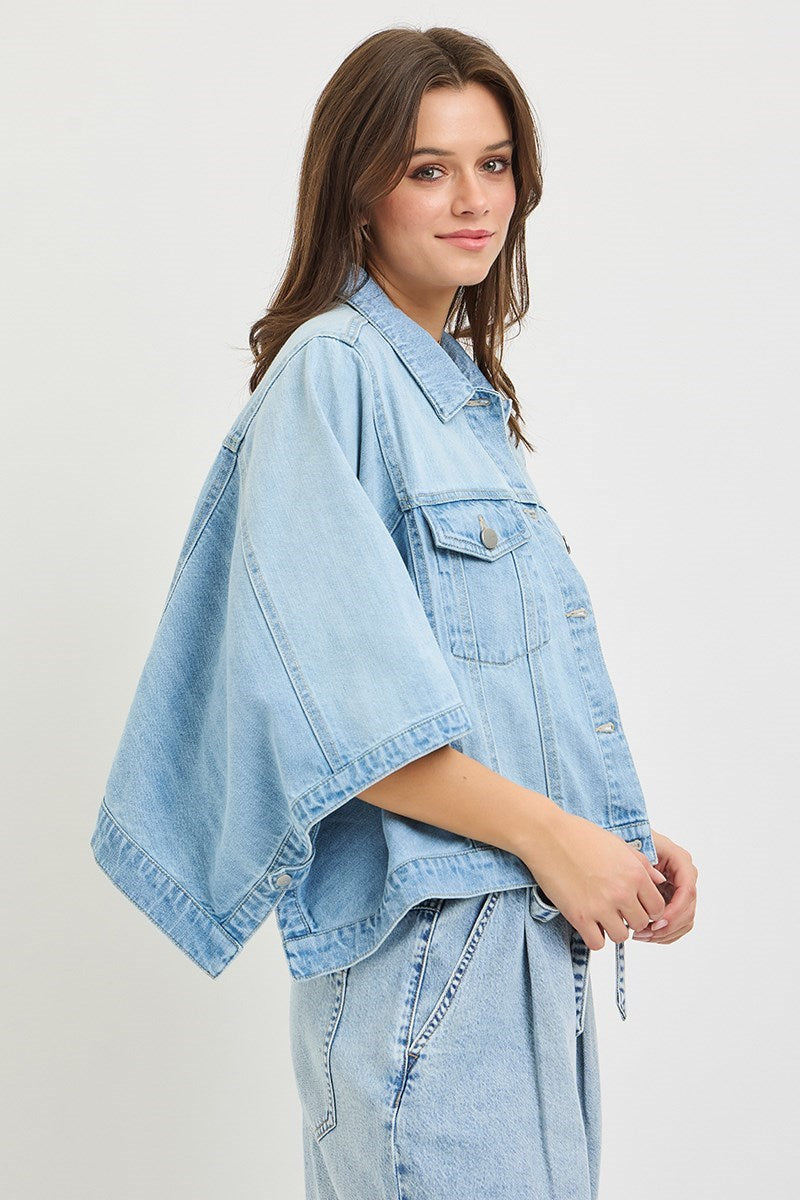 Woman wearing denim cape jacket on plain background