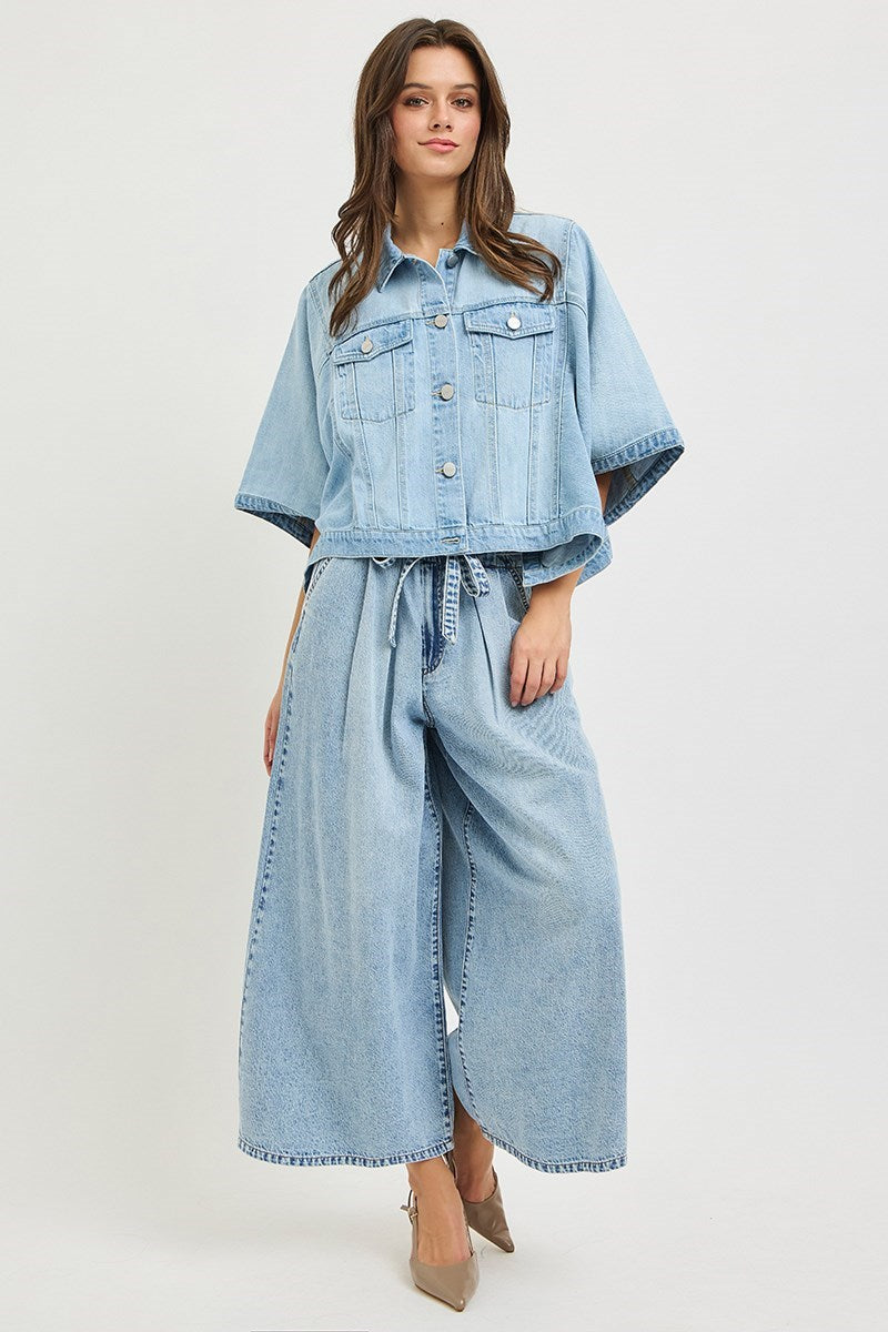 Woman wearing denim cape jacket and jeans on plain background