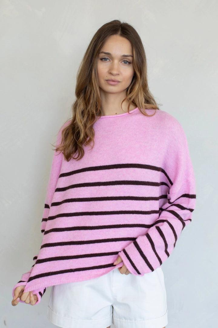 Woman wearing a pink and black striped sweater against a plain background