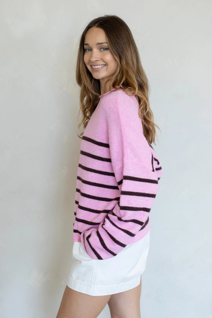 Woman wearing a pink and black striped sweater against a plain background