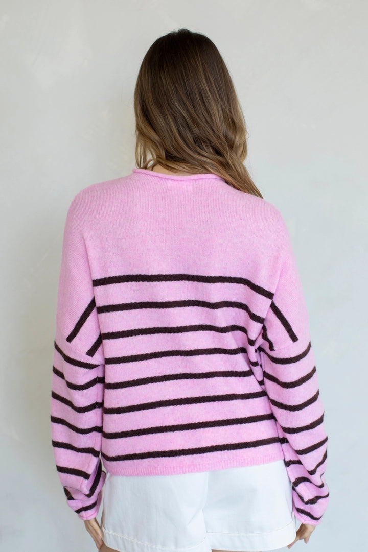 Person wearing a pink sweater with black stripes against a plain background