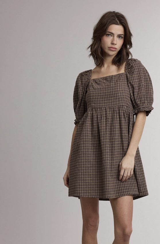 A woman modeling a brown and beige plaid puff-sleeve mini dress with a square neckline, standing against a plain light gray studio background.