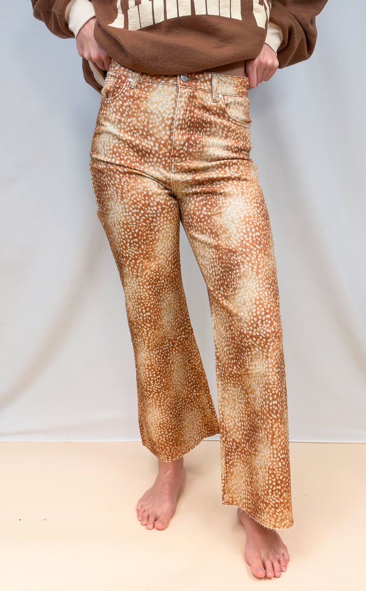 Woman shown from waist down wearing fawn print pants on plain background