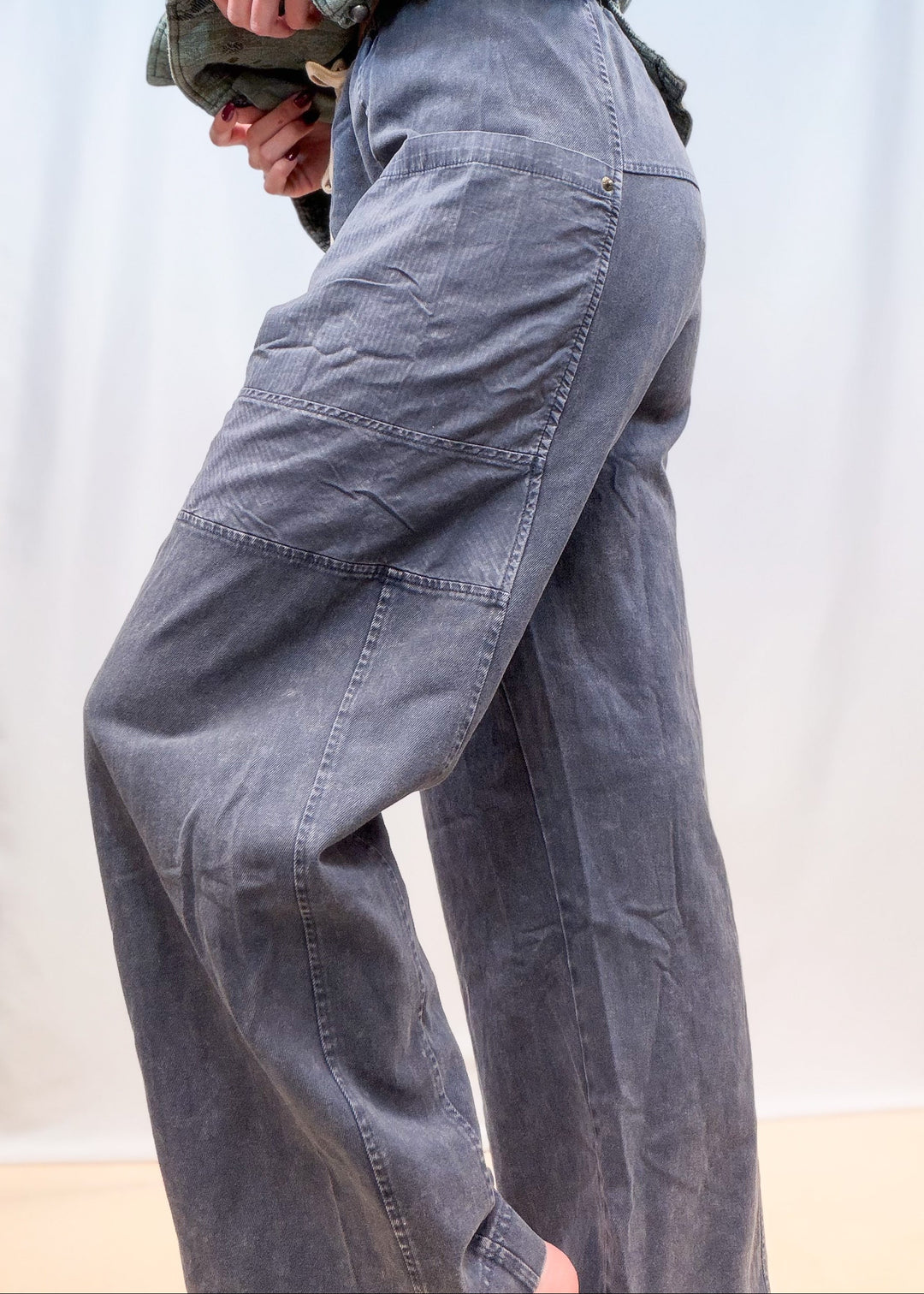 Woman shown from side view waist down wearing blue twill pants on plain background
