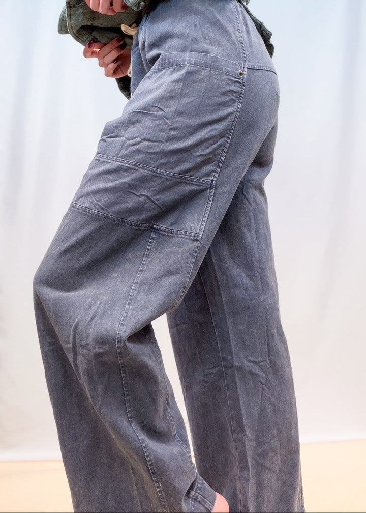 Woman shown from side view waist down wearing blue twill pants on plain background