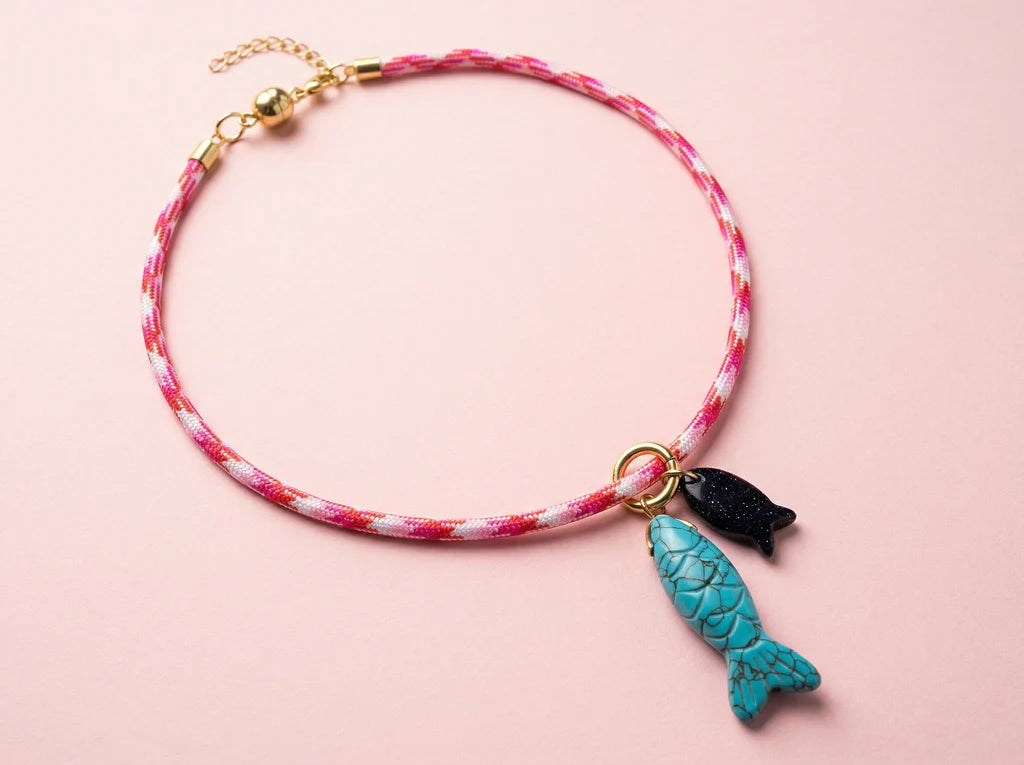 Necklace with fish charm on a pink background