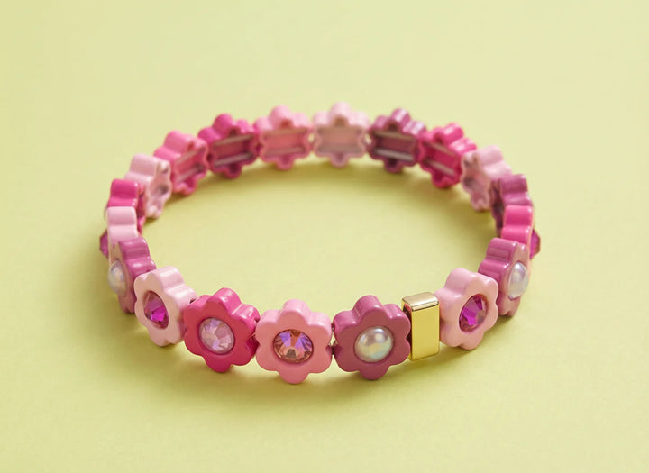 Pink beaded bracelet with flower-shaped beads on a light yellow background