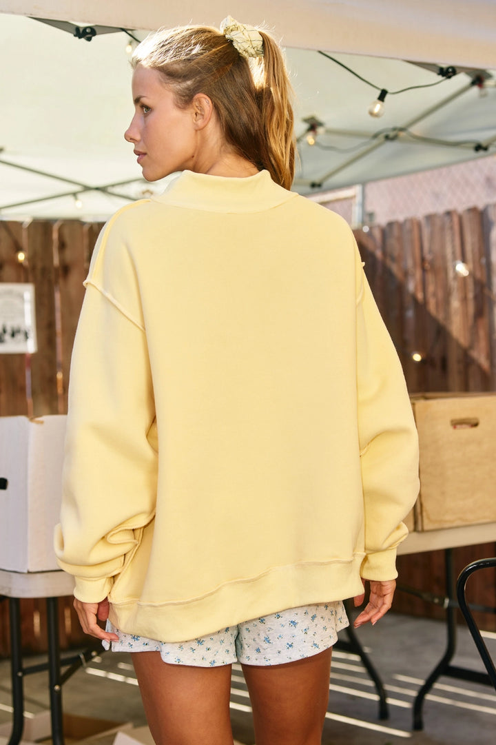 Person wearing a yellow sweatshirt and floral shorts in an outdoor setting