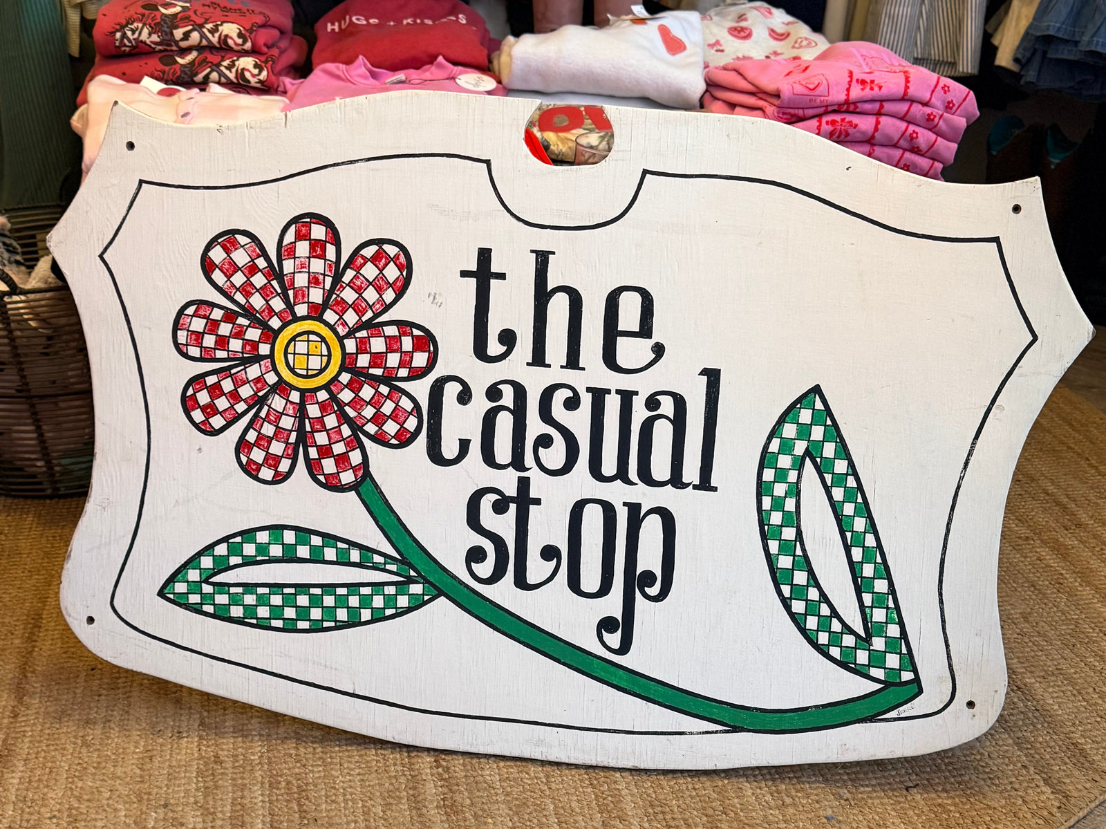 Store sign for 'the casual stop' with floral design in a clothing store.