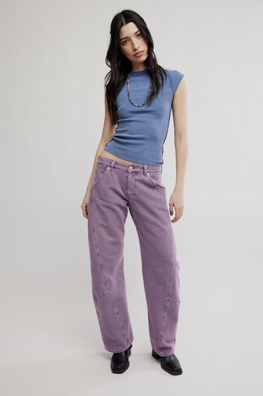 Woman wearing purple pants and blue top on white background