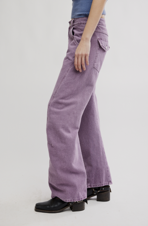 Woman wearing purple pants and blue top on white background