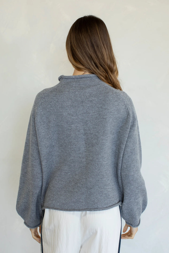 back of woman wearing grey sweater on plain background