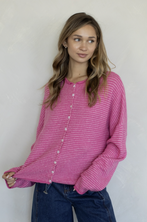 Woman wearing pink stripe cardigan and jeans on plain background