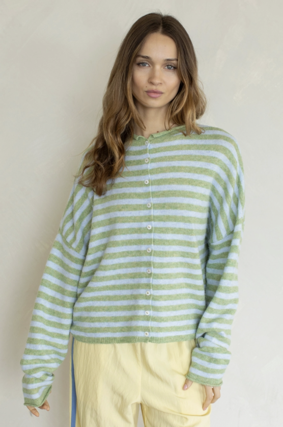 Woman wearing green stripe cardigan and yellow pants on plain background