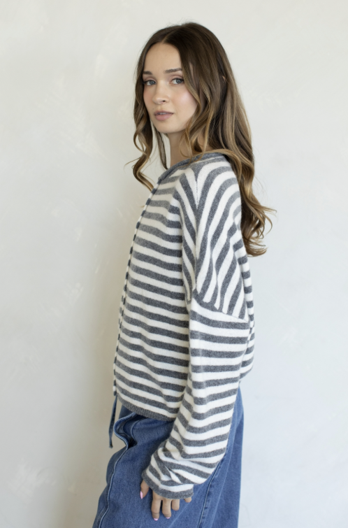Woman wearing grey and ivory stripe cardigan on plain background