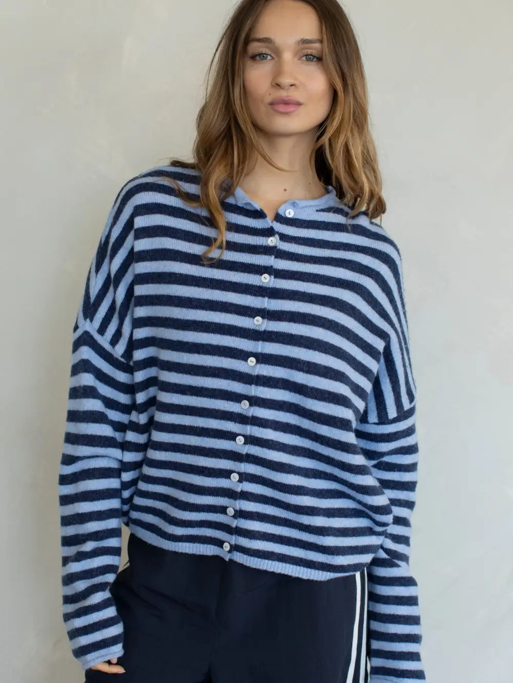 Woman wearing a blue and white striped sweater against a plain background