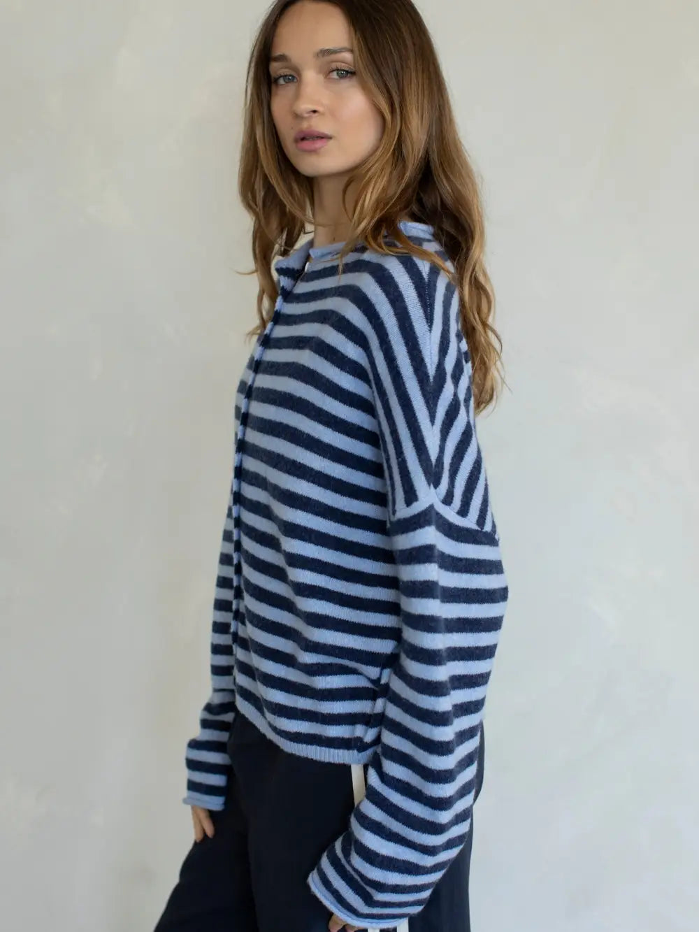 Woman wearing a blue and white striped sweater against a plain background