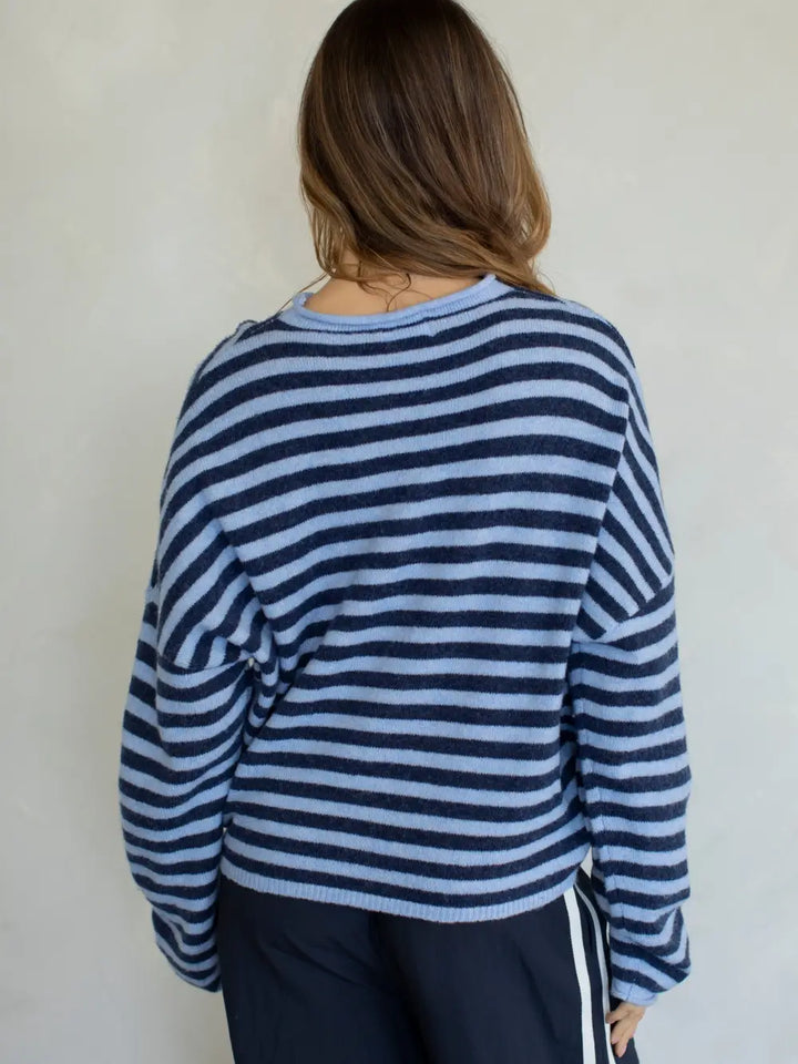 Person wearing a blue and white striped sweater against a plain background