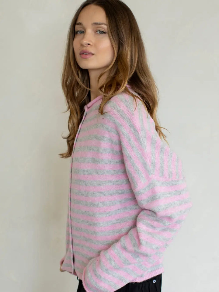 Woman wearing a pink and gray striped sweater against a plain background