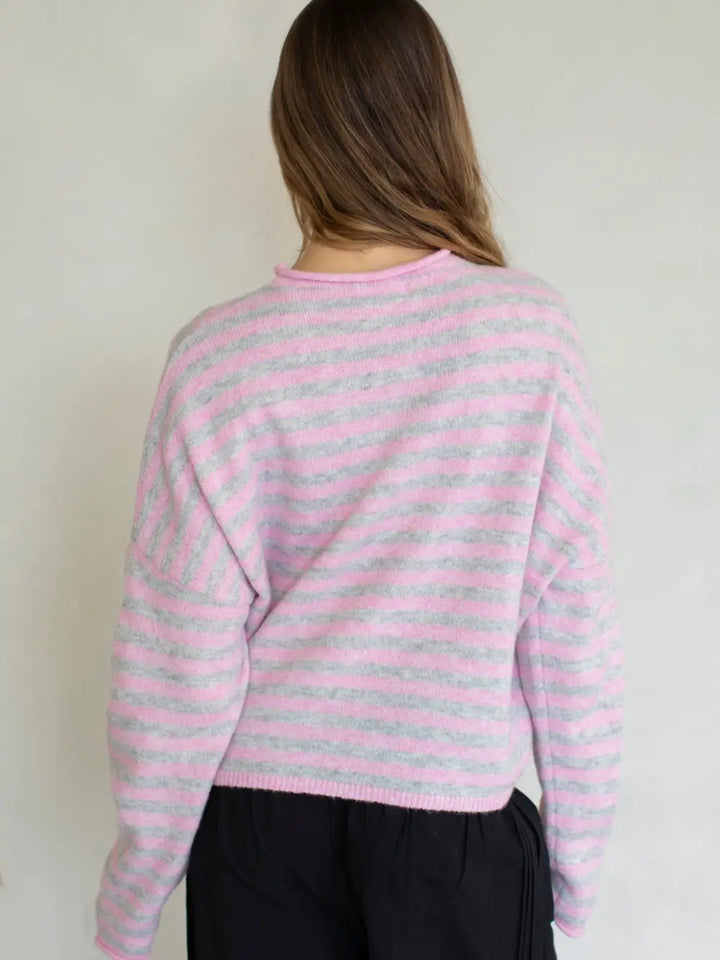 Person wearing a pink and gray striped sweater against a plain background