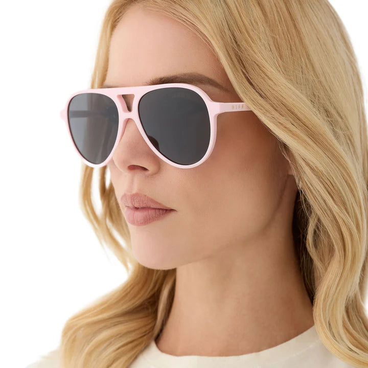 Close-up of a person wearing pink sunglasses with a neutral background