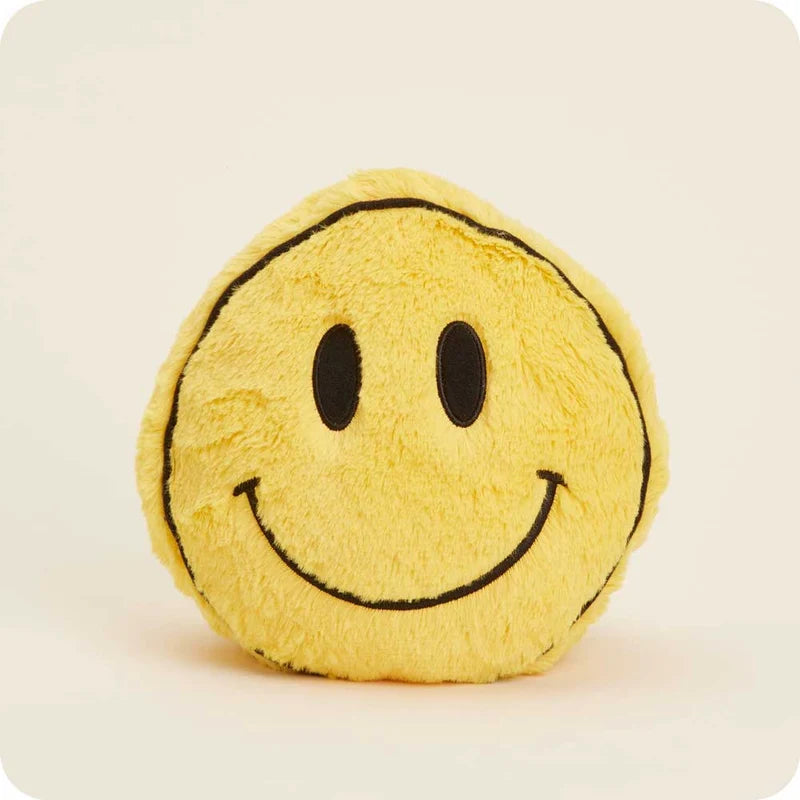 A round yellow plush smiley face pillow with black embroidered eyes and a curved smile, shown against a plain light beige background.