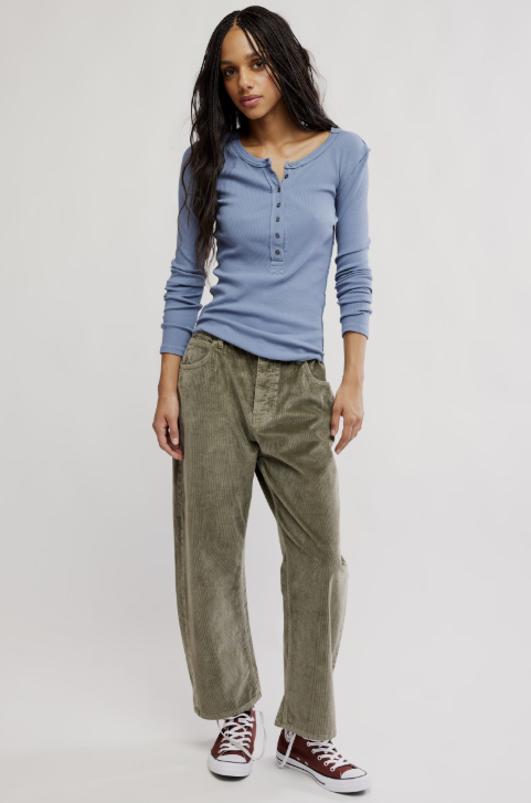 Woman wearing a blue long-sleeve shirt and green pants on a white background
